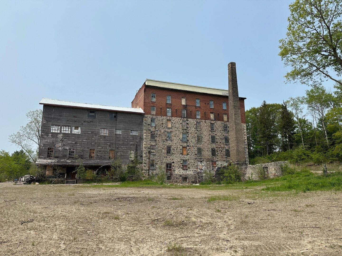 The surviving stone, brick and timber Greenfield Mill building today, with its tall chimney