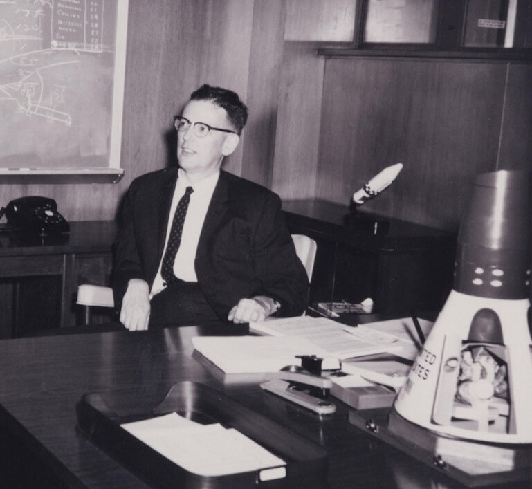 Jim Chamberlin at his NASA desk in 1962, with a Mercury spacecraft model